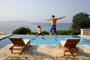 Ric Caesar and son jumping into a pool in Greece.